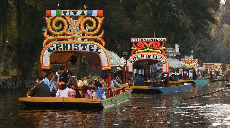 Two colorful trajineras (traditional Mexican boats) navigating the canals of Xochimilco, Mexico City, showcasing the vibrant atmosphere of the famous floating gardens