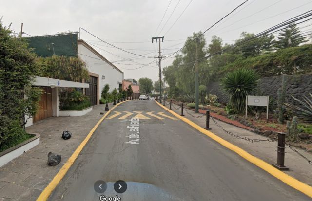 Car-view of Pedregal neighborhood in Mexico City, showcasing luxurious homes nestled amidst volcanic rock formations and lush vegetation.