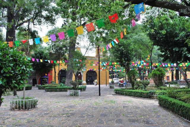 Cobblestone streets lined with colorful buildings and greenery in Coyoacán.