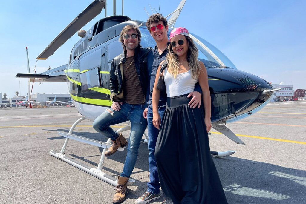 A group of happy passengers posing in front of a helicopter before embarking on a Mexico Helicopter Tours