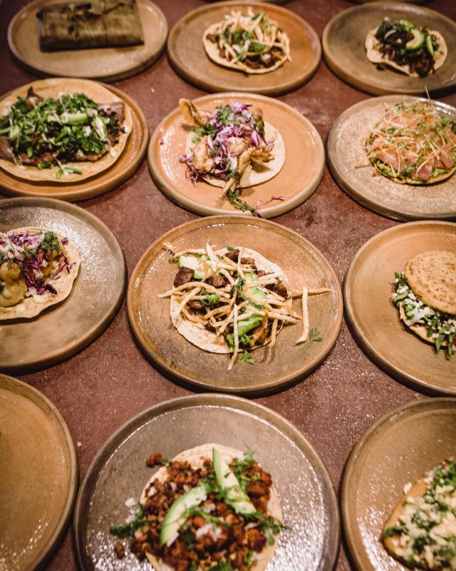 An array of tacos served on round plates, each with unique toppings.